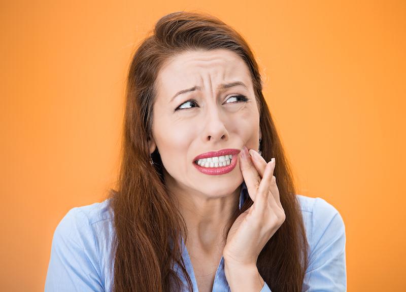 Woman holding face with severe tooth pain