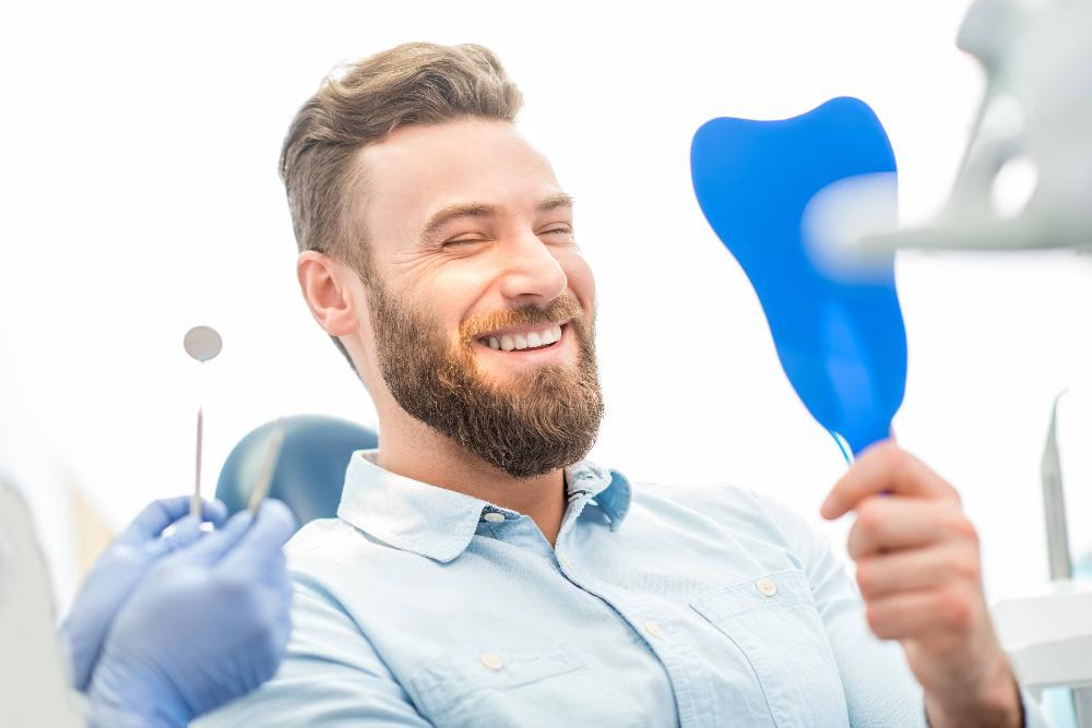 Patient smiling looking into hand mirror at dentist near me Springfield IL