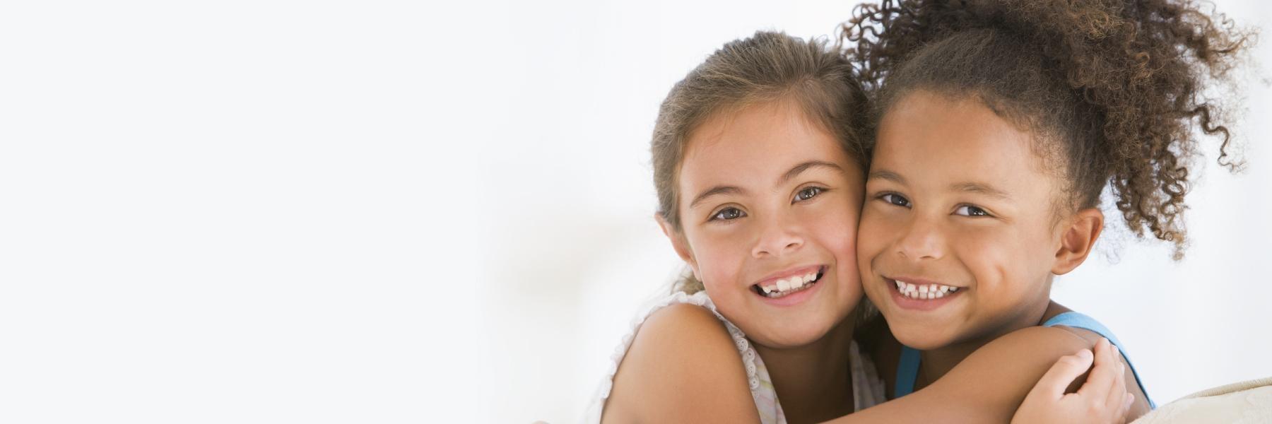 Two young girls smiling at childrens dentist in Springfield IL